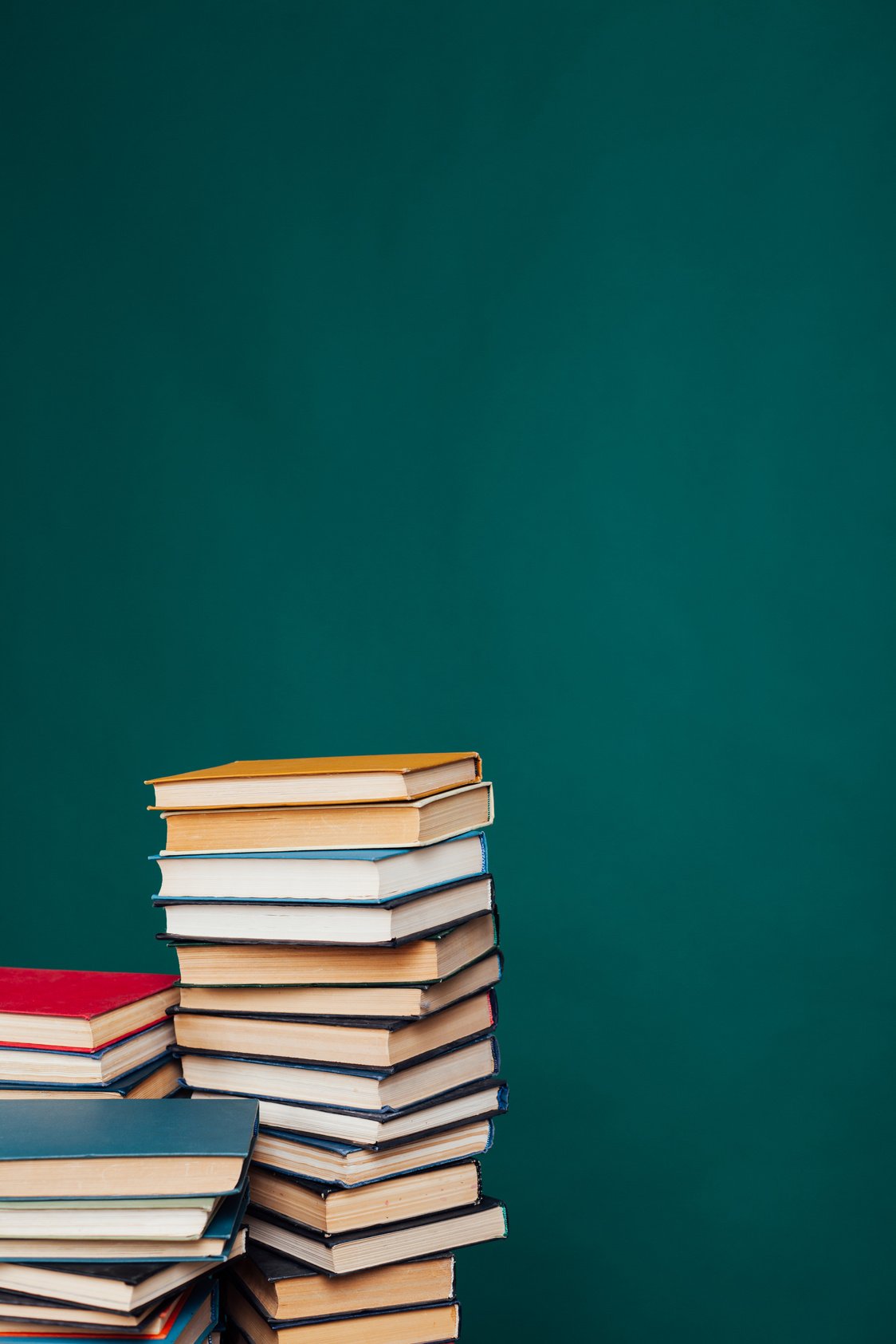 many stacks of educational books for learning preparation for college exams on a green background